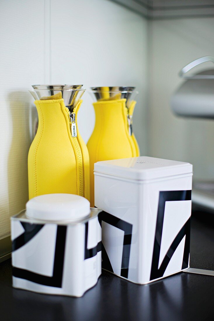 Storage jars with black and white graphic patterns and thermos flasks in yellow neoprene cosies