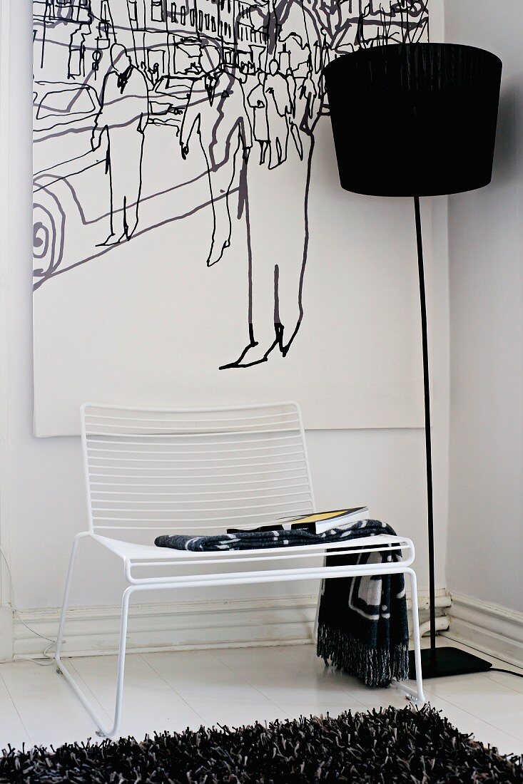 Delicate white Spaghetti Chair and black standard lamp in front of picture in corner