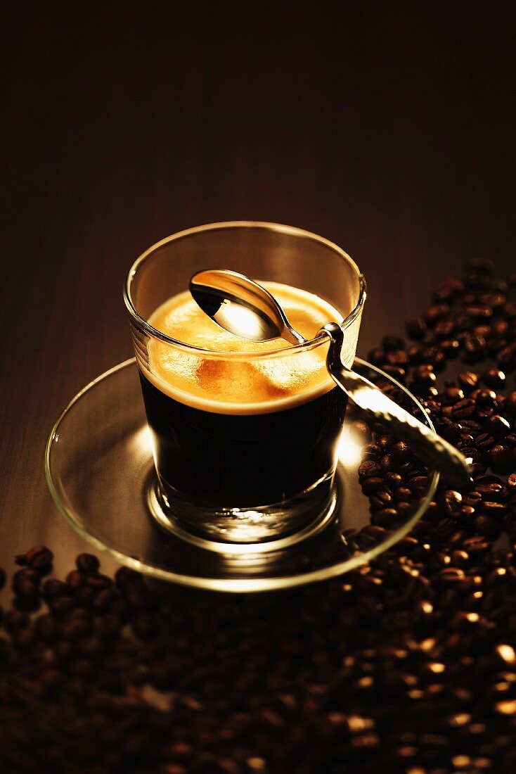 Ein Glas Espresso mit Löffel und Kaffeebohnen
