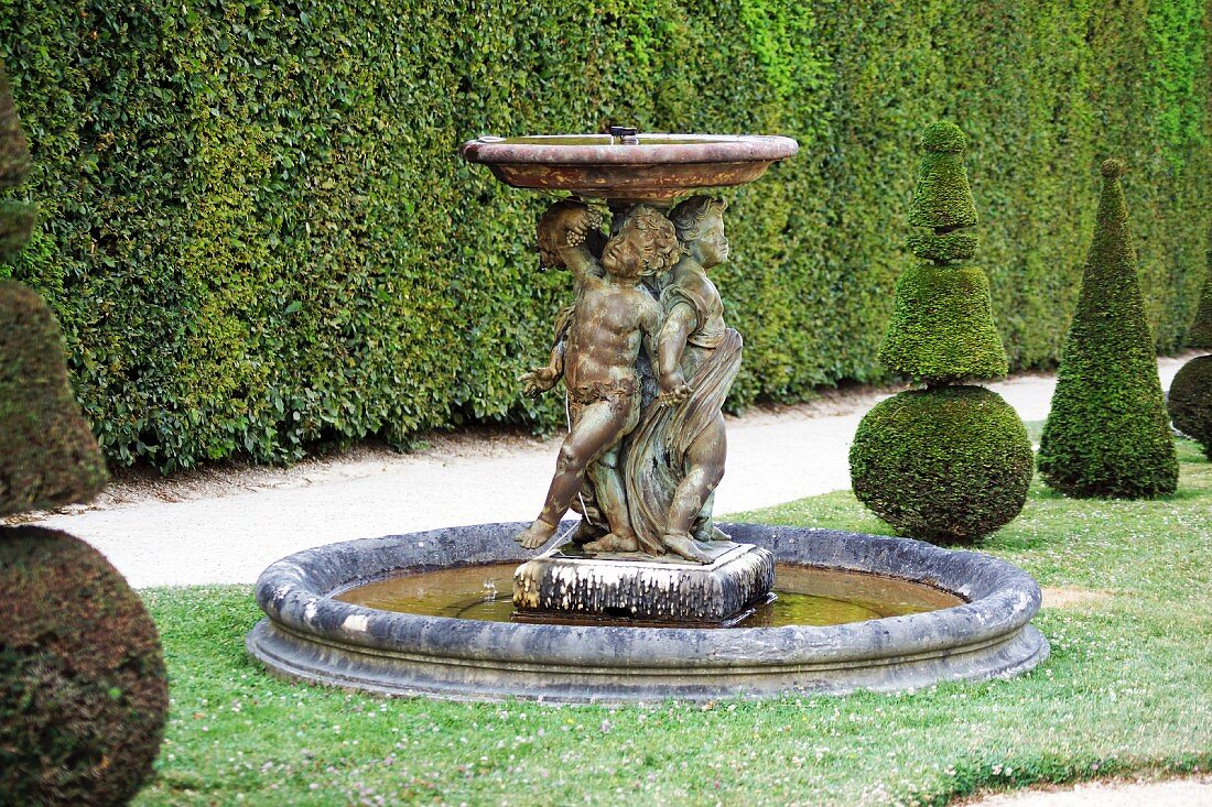 Springbrunnen mit Steinfiguren und formgeschnittene Buchsbäume (Versailler Schlosspark)