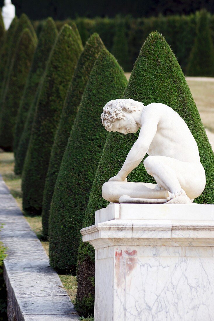 A stone figure on a plinth in the Garden of the Palace of Versailles