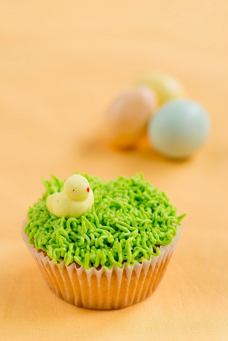 A vanilla cupcake decorated with grass and a chick for Easter