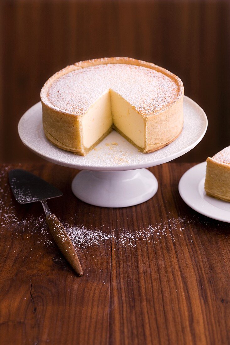 A cheesecake on a cake stand (sliced)