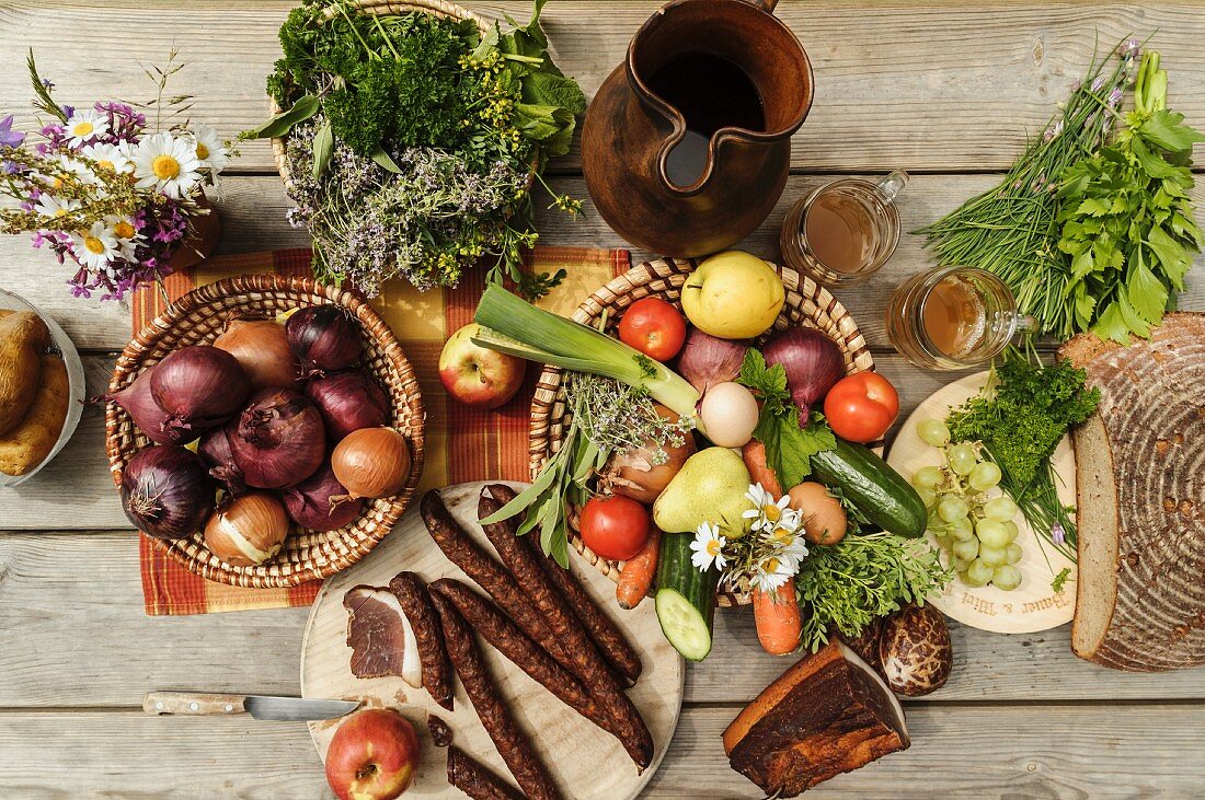 A bird's-eye view of a table laid with onions, a jug of must, vegetables, fruit, bacon, bread and snack sausages, Austria