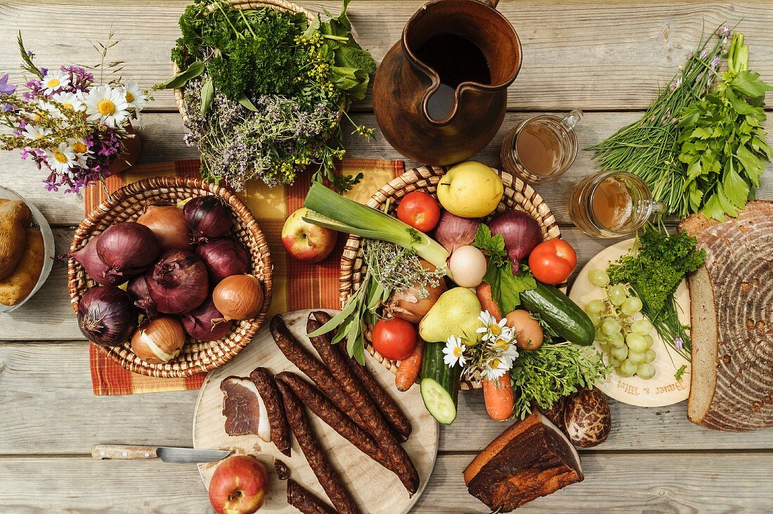 Jausentisch mit Zwiebeln, Mostkrug, Gemüse, Obst, Speck, Brot und Jausenwürste von oben