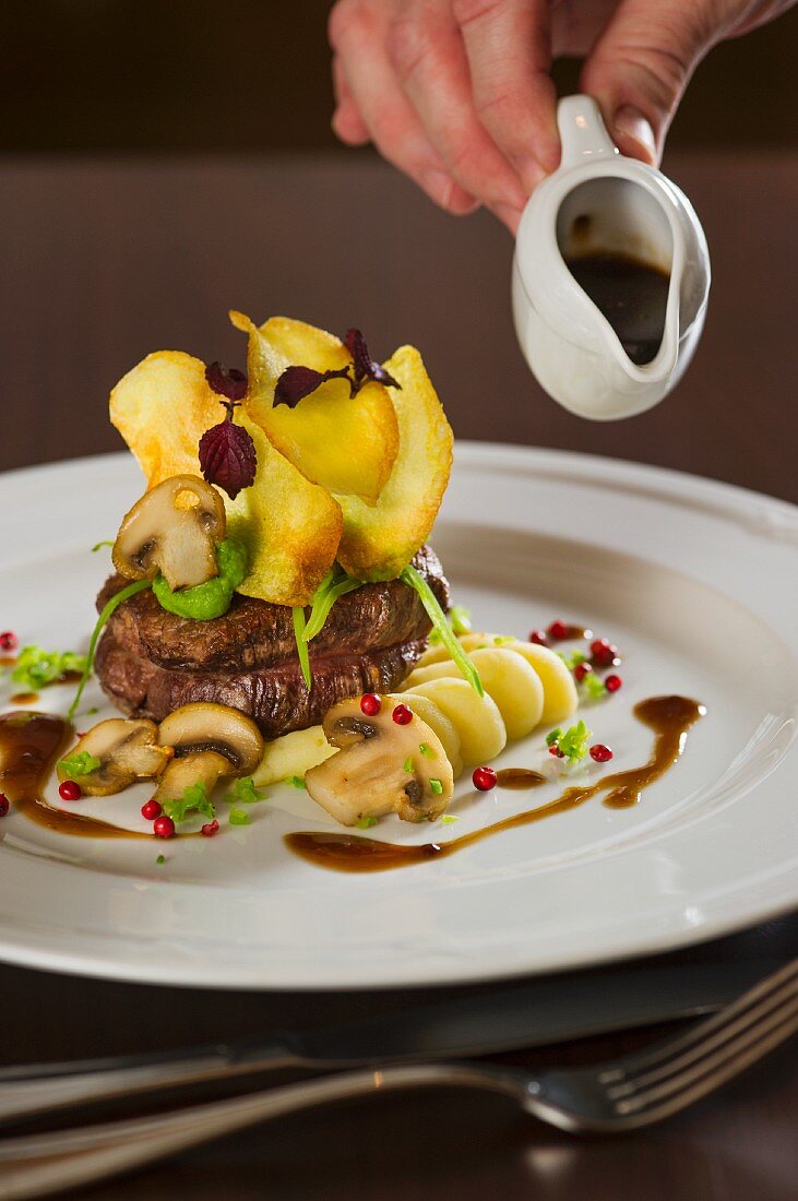 Rinderfilet mit Kartoffelchips und Pilzen mit Sauce beträufeln