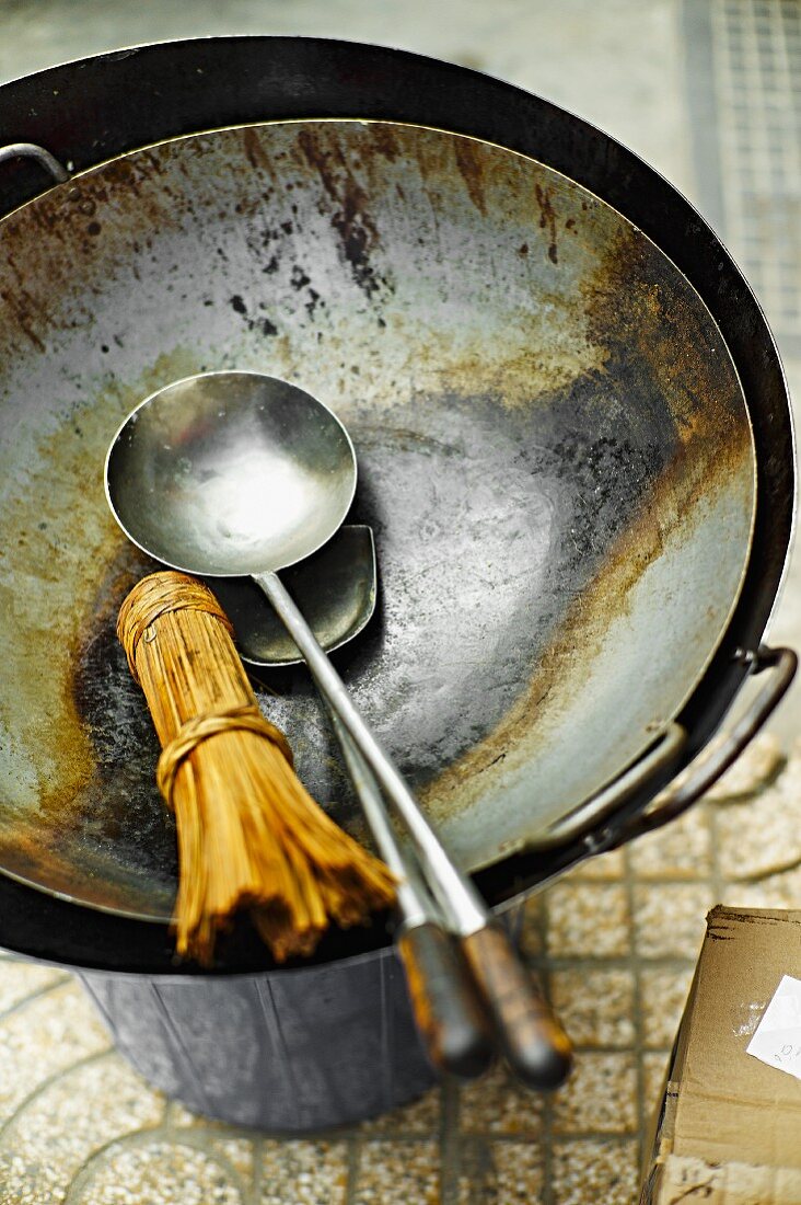 A bamboo whisk, a ladle and a spatula in a wok at a market in Saigon (Vietnam)