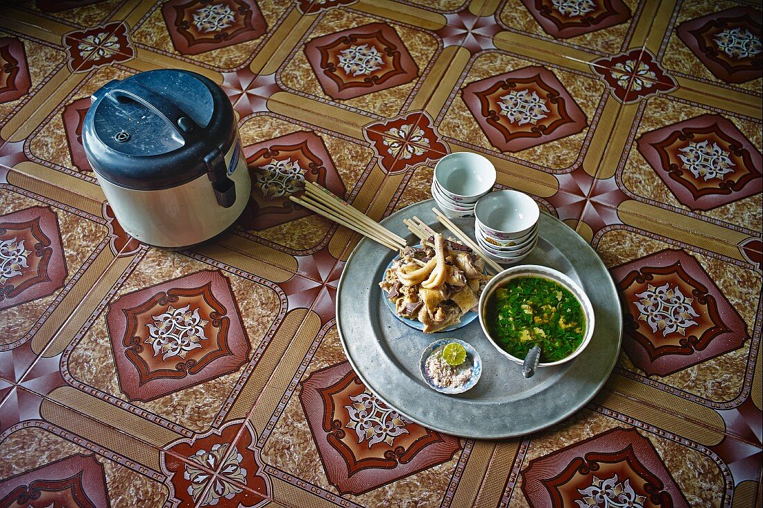 Pho ga (Vietnamese chicken soup) on a tray with ingredients