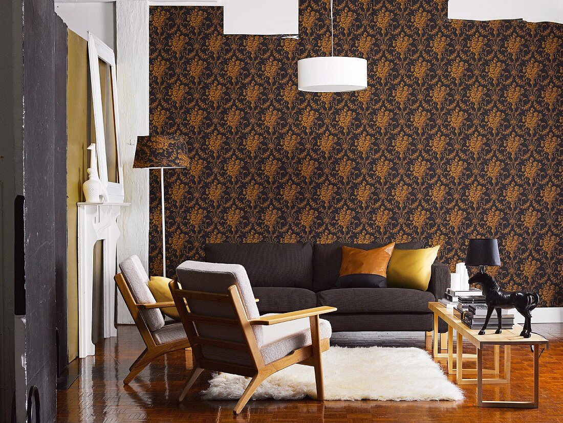 Living room with dark sofa, fifties-style armchairs and flokati rugs against elegant, dark patterned wallpaper