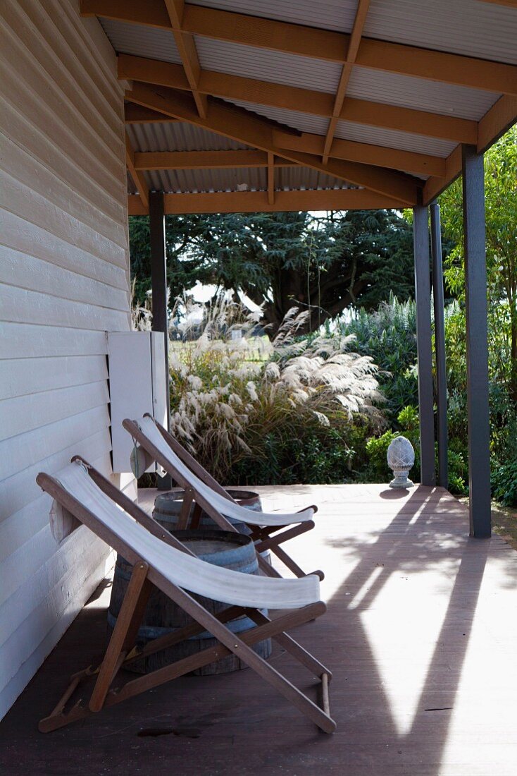 Wooden deckchairs on roofed terrace of wooden house