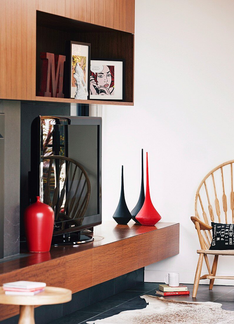 Extravagant black and red vases and TV on fitted 70s shelves