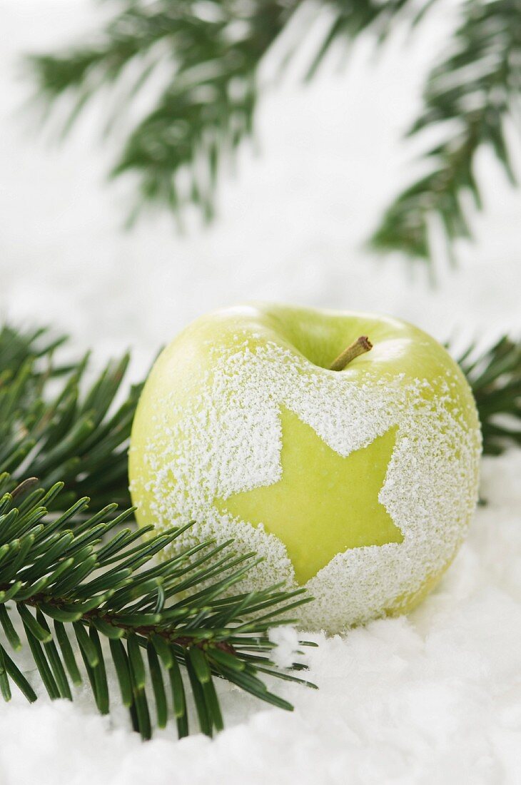 An apple decorated with a star in the snow