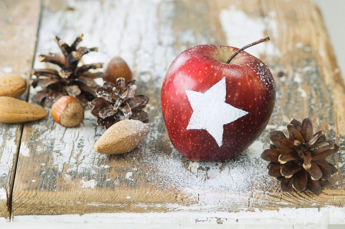 Apfel mit Sternmuster, Nüsse und Zapfen als Weihnachtsdeko