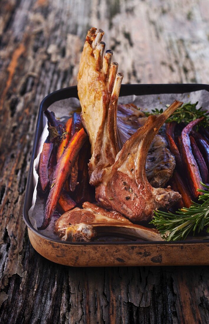 Lamb loin rack joint with roasted carrots in a roasting dish