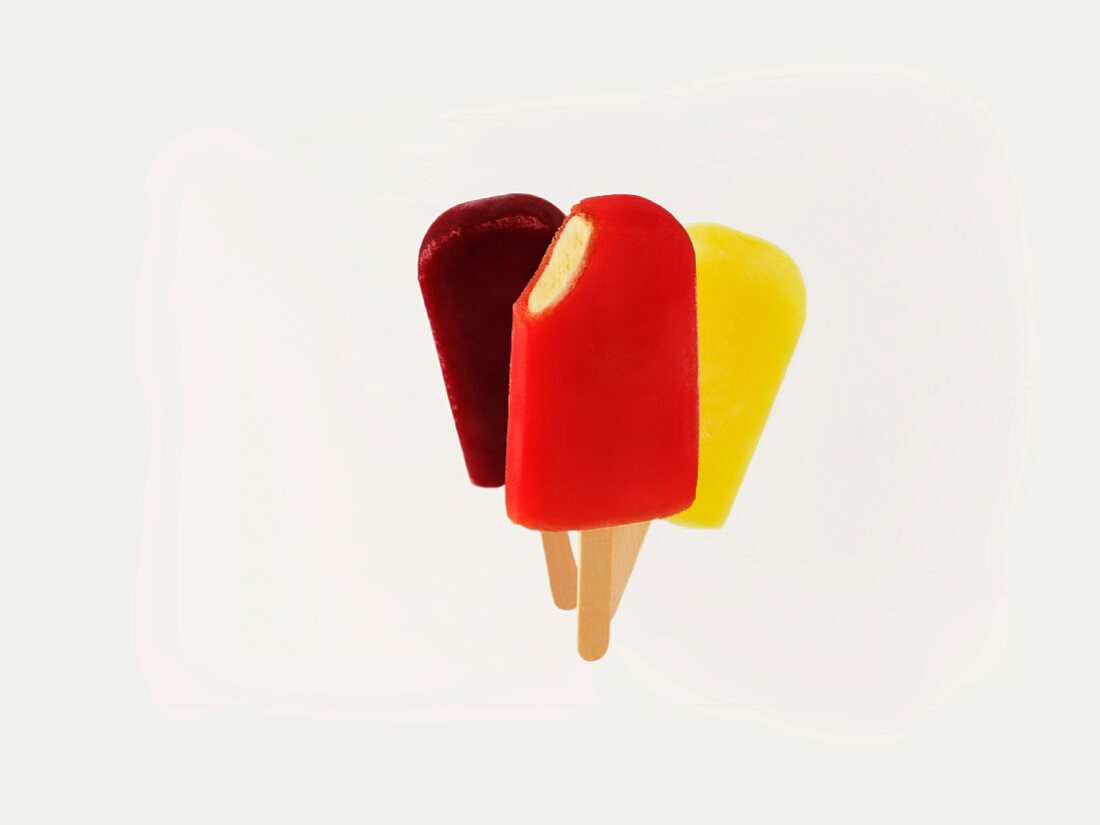 Three different coloured fruit ice cream sticks against a white background