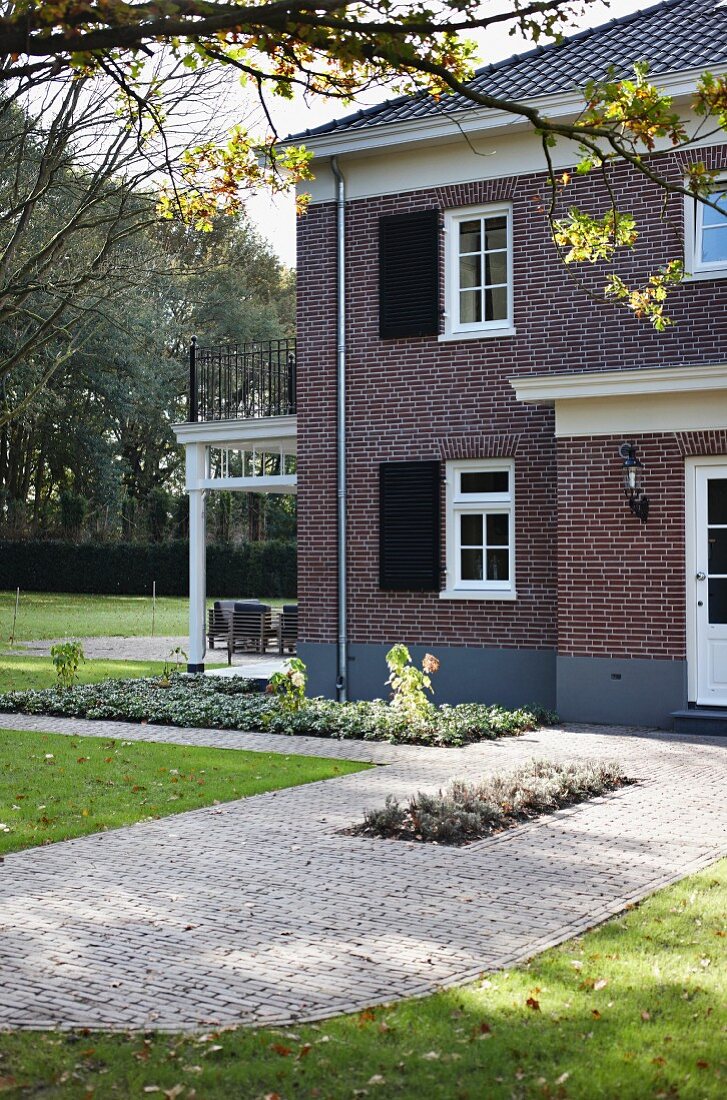 Two-storey villa with brick facade and veranda in garden