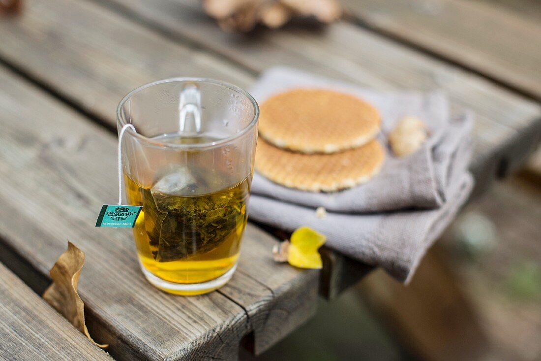 A cup of tea and syrup waffles on a wooden table in a garden