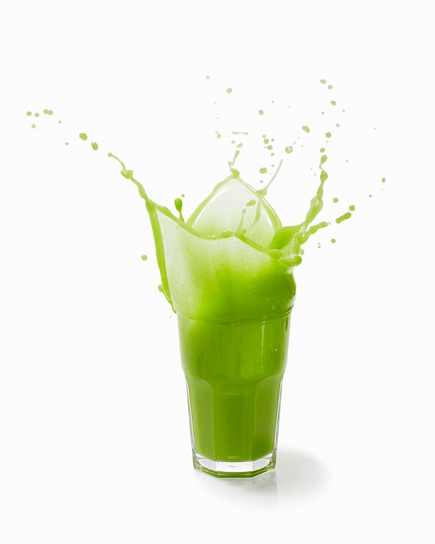 A splashing vegetable smoothie against a white background