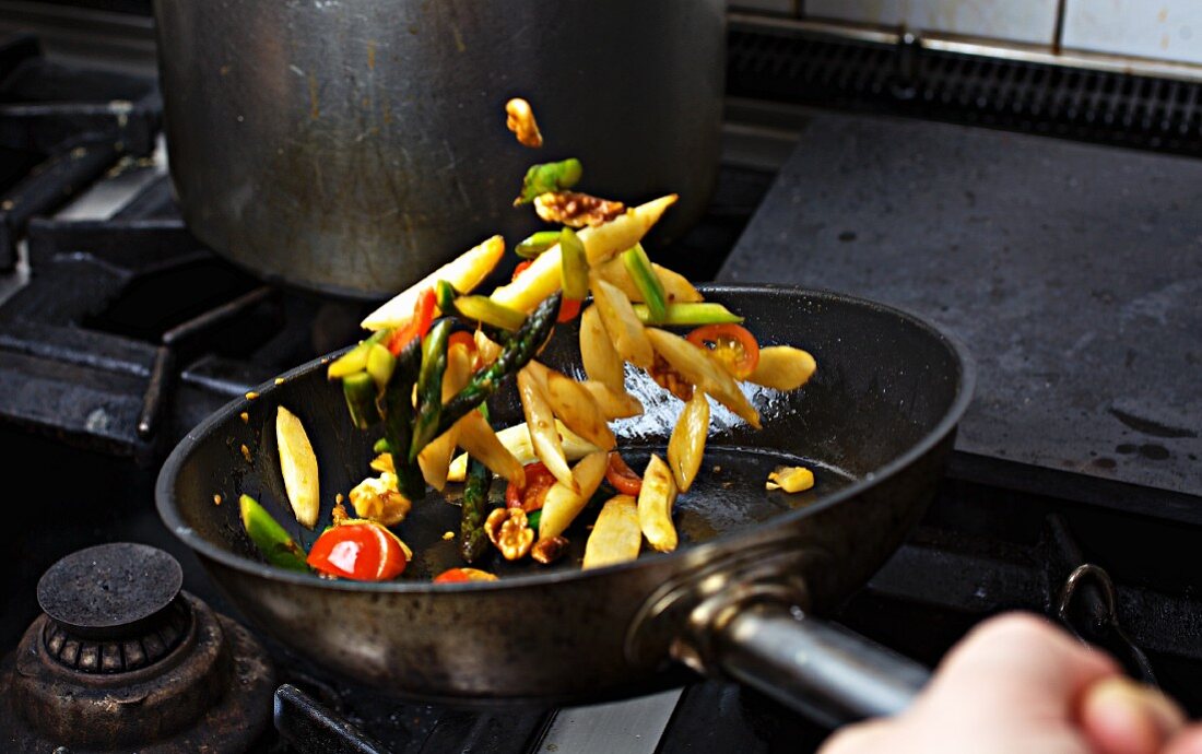 Vegetables being sauteed in a pan on a hob