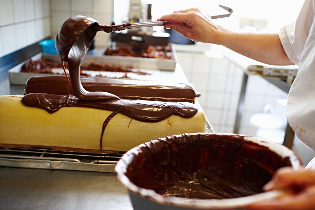 A cake being covered with chocolate glaze