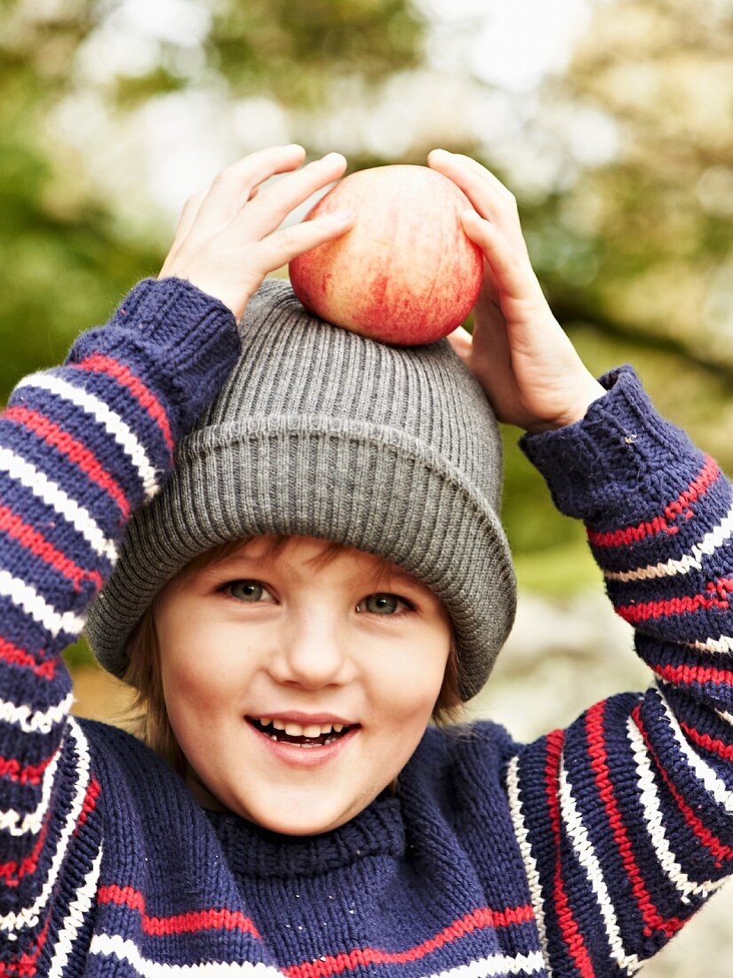 A little girl holding an apple on her head at an autumnal picnic