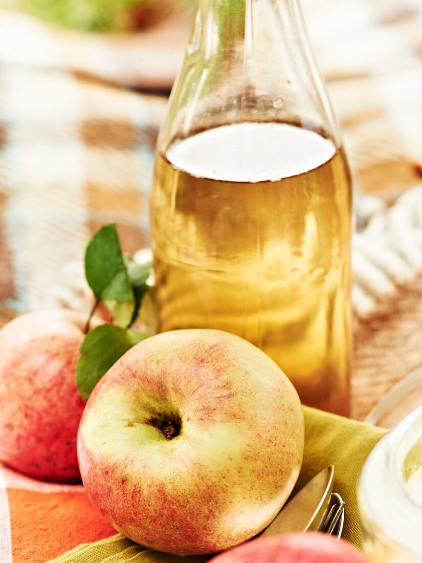 Eine Flasche Apfelsaft und frische Äpfel beim Herbstpicknick