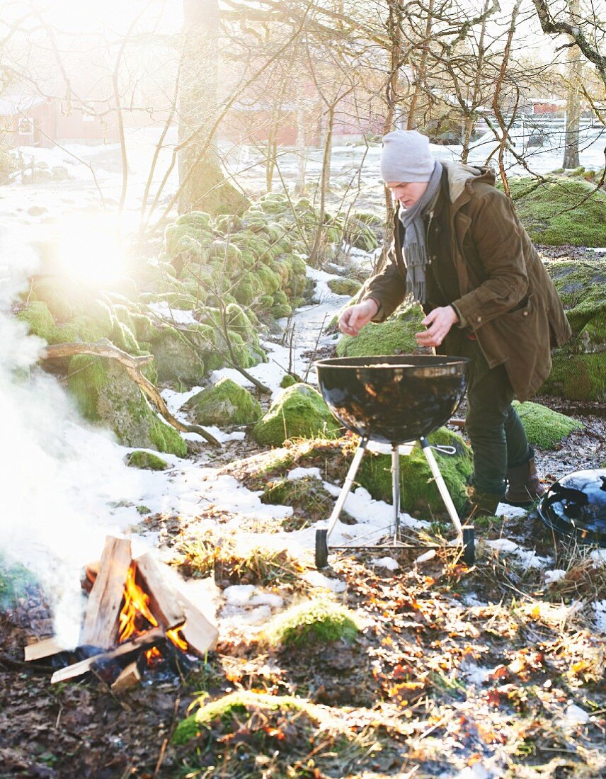 A man grilling a pizza in a wintry garden
