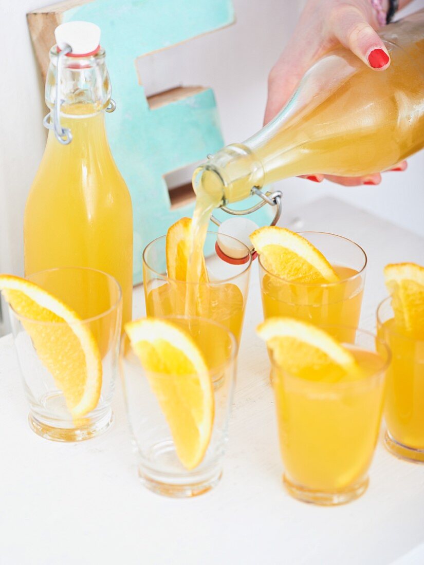 Homemade orange and ginger lemonade being poured into glasses