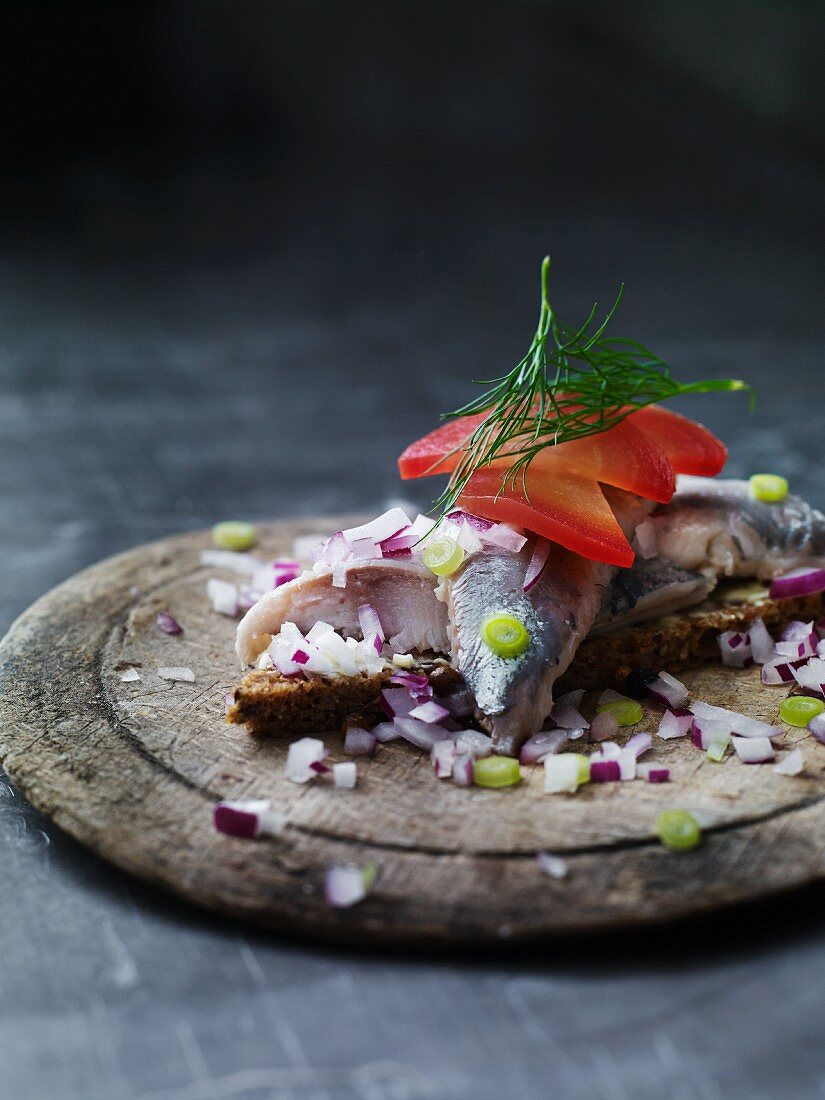 A slice of bread topped with herring and red onions