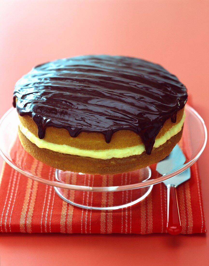 A whole Boston Cream Pie on a glass cake stand (USA)