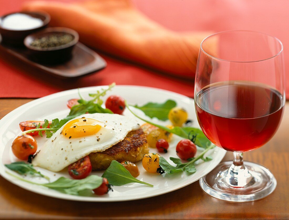 A crab cake topped with a fried egg and served with cherry tomatoes and rocket