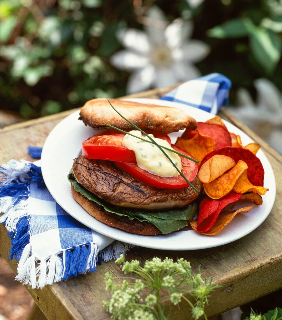 Veggie-Burger und Gemüsechips auf Holzbrett im Garten