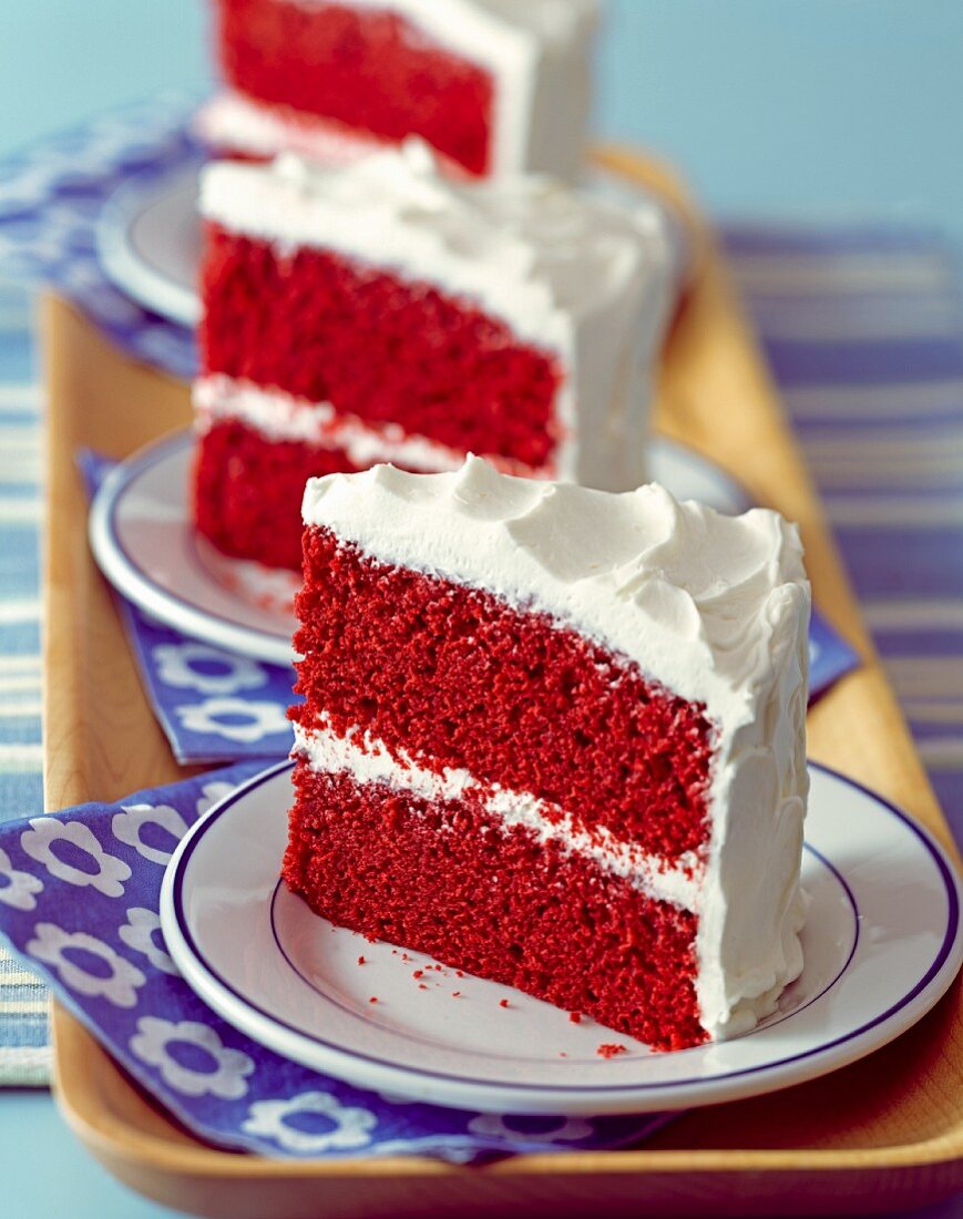 Drei Stücke Red Velvet Cake auf Kuchentellern (USA)