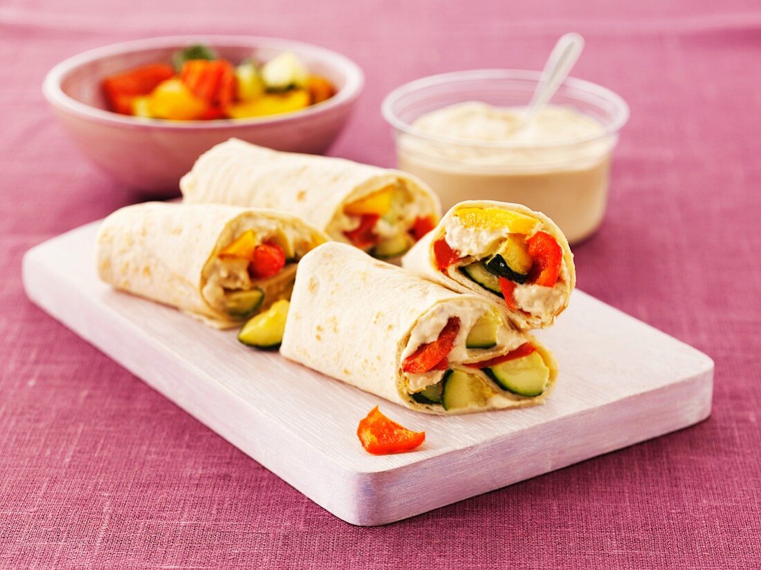Wraps with hummus, courgette and peppers on a board