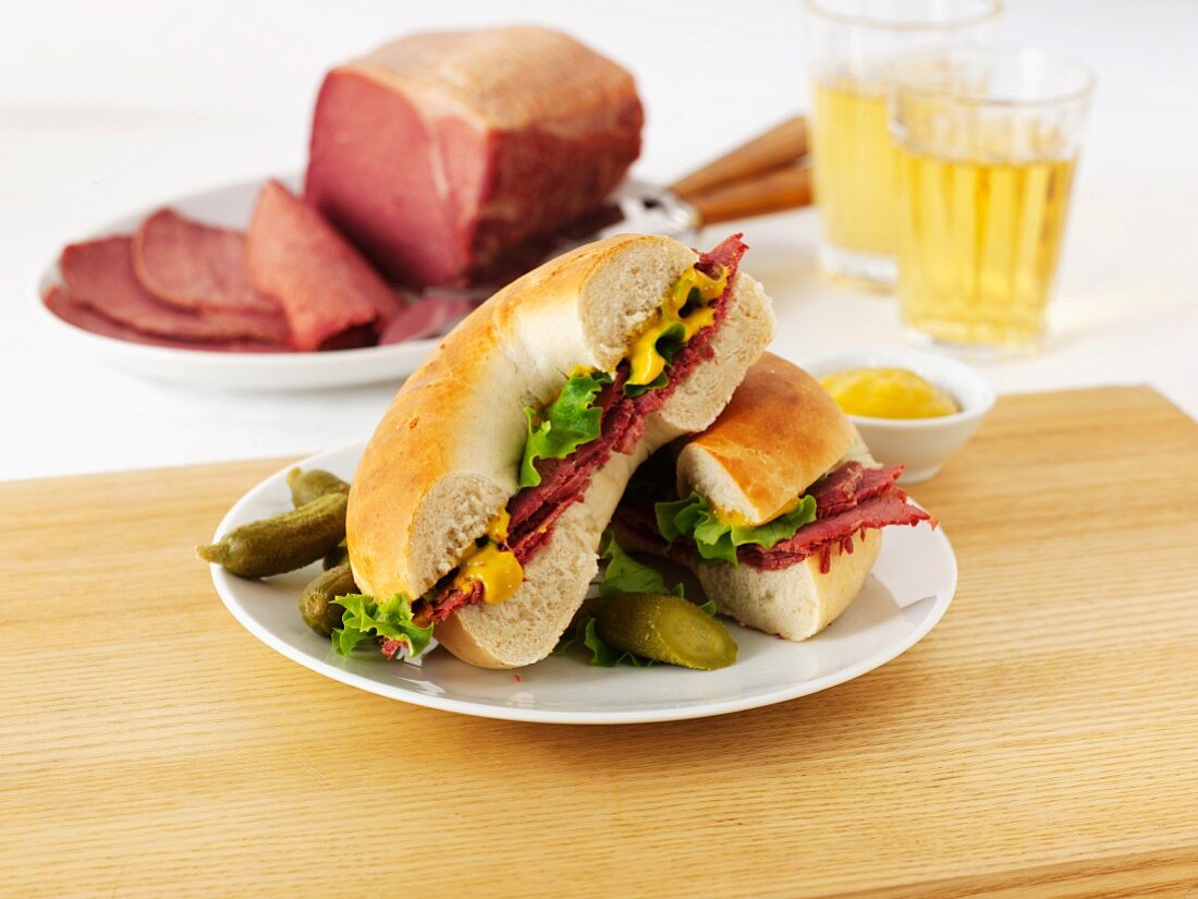 A pastrami, salad and mustard bagel served with gherkins