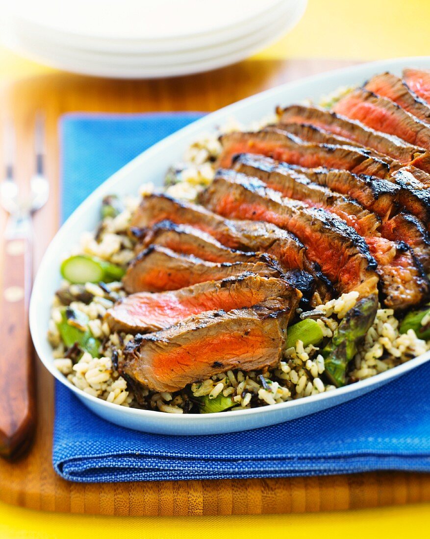 Sliced beef steak on an asparagus and rice salad