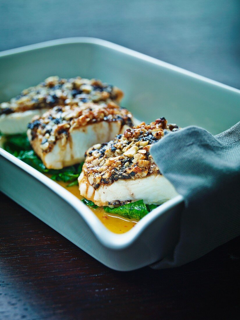 White halibut with an olive brittle crust served on steamed spinach and orange and pepper butter