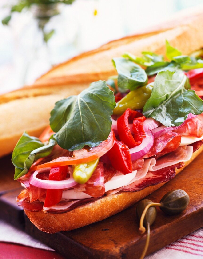 A lavishly topped baguette with ham, salami, cheese and vegetables