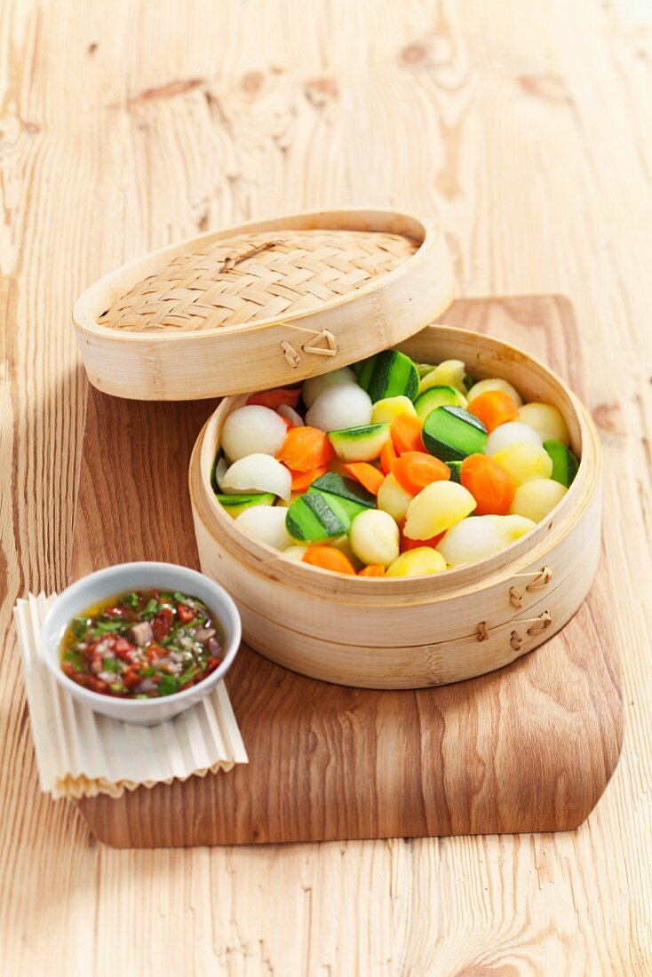 Vegetables in a bamboo steamer served with dried tomato sauce