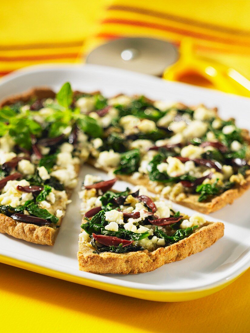 A wholemeal pizza topped with spinach, feta cheese and olives
