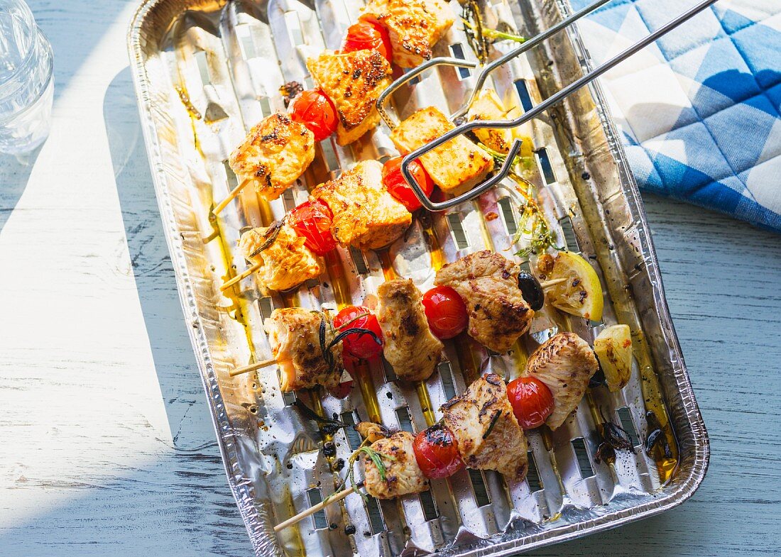 Turkey skewers with tomatoes and olives on an aluminium tray
