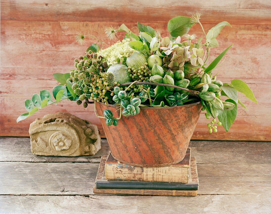 Late summer arrangement with poppy seed heads, hydrangeas and blackberries in pot