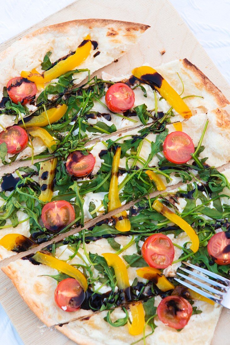 Gemüsepizza mit Rucola, Kirschtomaten und Paprika