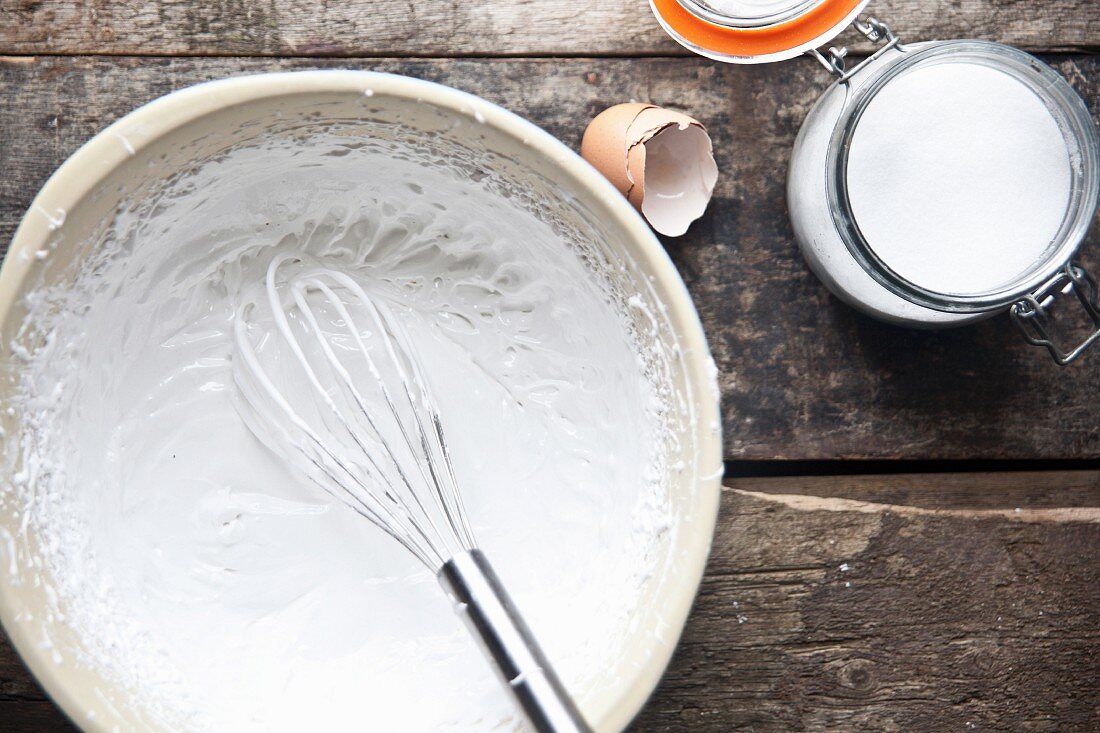 Eischnee mit Zucker und Schneebesen in einer Schüssel