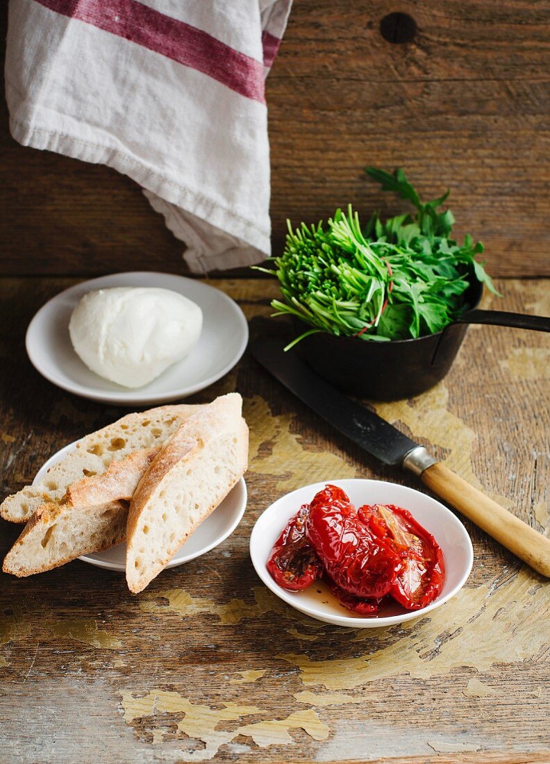 Weissbrotscheiben, getrocknete Tomaten, Mozzarella und Rucola