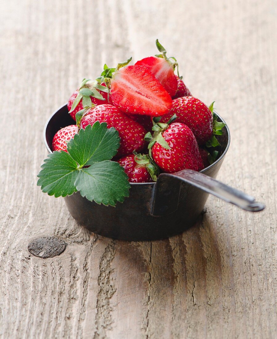 Frische Erdbeeren mit Blättern im Stieltopf