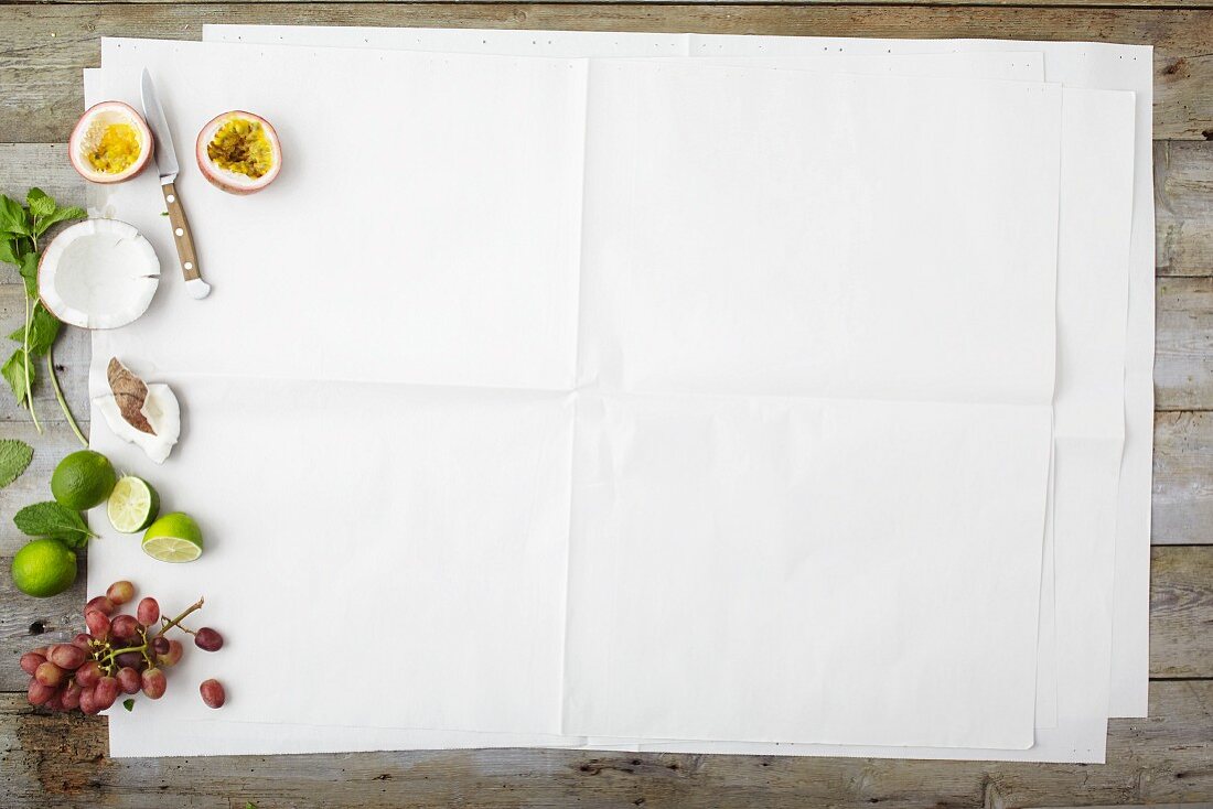 Früchte und Kokosnuss am Bildrand von weißem Papier