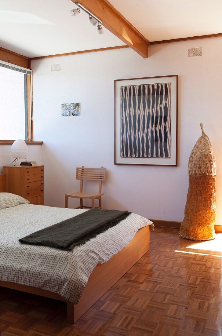 Double bed in bedroom with pandan leaf fish trap next to framed picture on wall