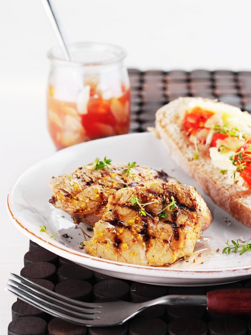 Grilled pork fillet served with a slice of bread and pickles