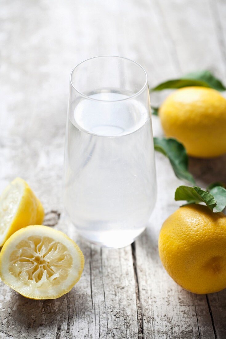 Ein Glas Zitronenwasser und frische Zitronen